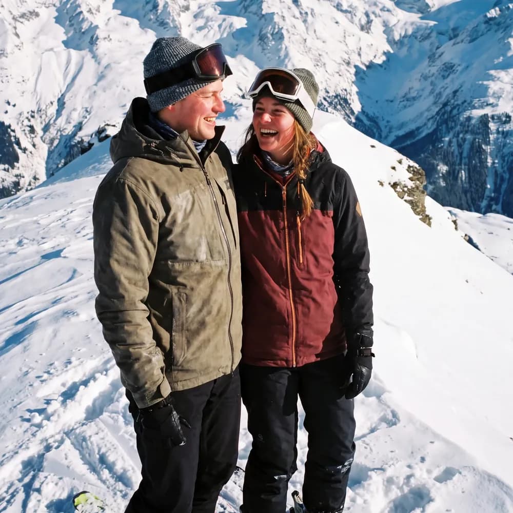 A couple on skis on a snowy ridge